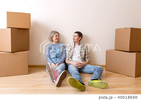 Photo of young married couple sitting on floor among cardboard boxes Photo of young married couple sitting on floor among cardboard boxes 40018690
