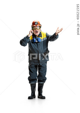 The studio shot of surprised senior bearded male miner standing at the camera with smartphone on a 40021595