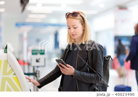 Casual caucasian woman using smart phone application and check-in machine at the airport getting the 40023490