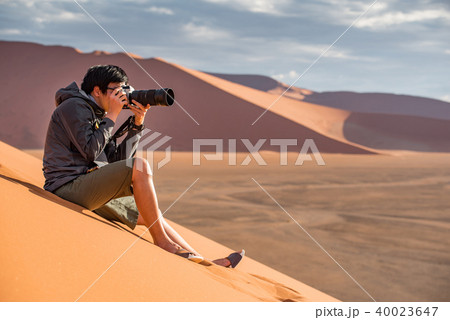 Asian man photographer taking photo on sand dune 40023647