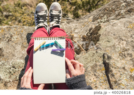 View from the first person on the female lap is a notebook with chalks for drawing pastels. Female 40026818