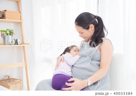 Pregnant mother breast feeding her daughter Pregnant mother breast feeding her daughter 40033384