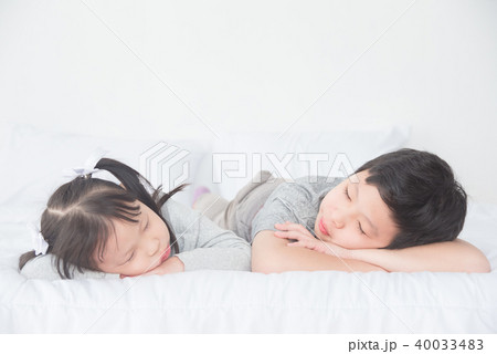 Two Asian siblings fall asleep on bed in day time 40033483