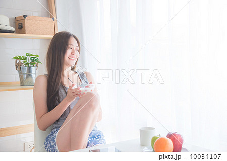 woman sitting near by window and holding yogert 40034107