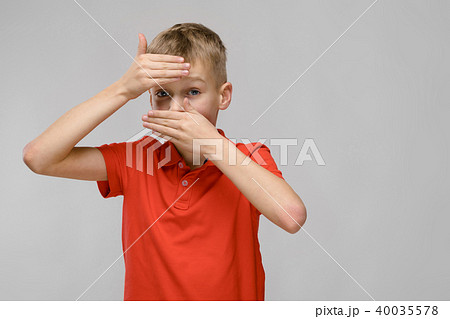 Portrait of blonde caucasian sad sick little boy in orange t-shirt closing his forehead and mouth 40035578