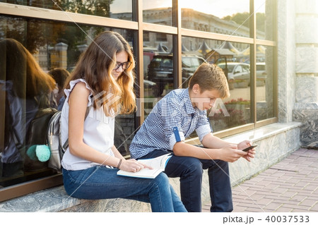 teenagers, reading book and using smartphone. 40037533