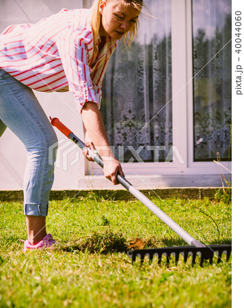 Woman using rake to clean up garden Woman using rake to clean up garden 40044060
