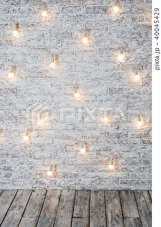 Light bulbs on white brick background with wooden floor. Vintage edison light bulbs garland in loft 40045429
