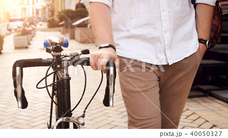 Closeup photo of young man with bicycle commuting to work 40050327