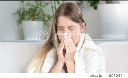 Portrait of young woman with cold using paper tissues Portrait of young woman with cold using paper tissues 40050444