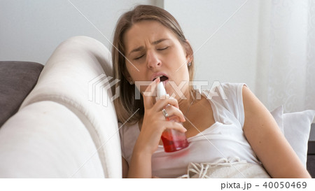 Portrait of young woman with fly using throat spray Portrait of young woman with fly using throat spray 40050469