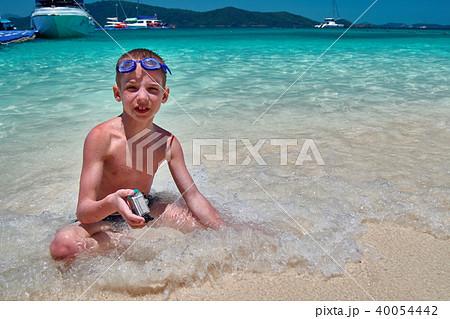 Boy with swimming goggles sits in turquoise water Boy with swimming goggles sits in turquoise water 40054442