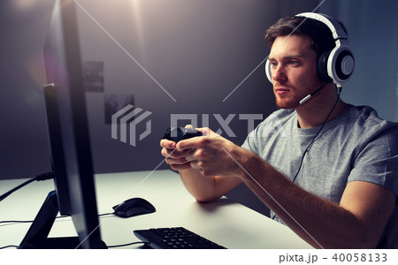 man in headset playing computer video game at home man in headset playing computer video game at home 40058133