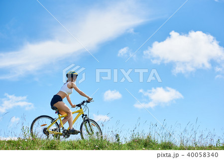 Young happy woman cycling on mountain bike at summer day 40058340