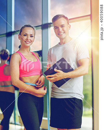 smiling young woman with personal trainer in gym smiling young woman with personal trainer in gym 40059088