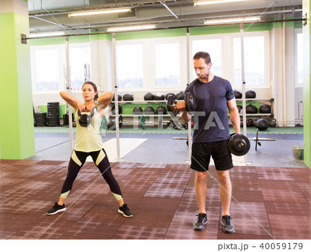 man and woman with kettlebell exercising in gym 40059179