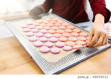 chef with macarons on oven tray at confectionery 40059522