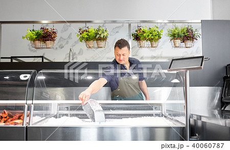 male seller adding ice to fridge at fish shop male seller adding ice to fridge at fish shop 40060787