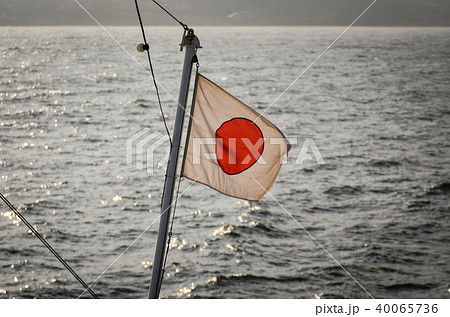 海上に浮かぶ船の上ではためく日本国旗の写真素材