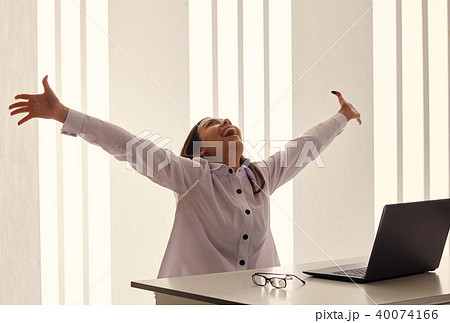 Young woman in office jubilates at desk.  40074166