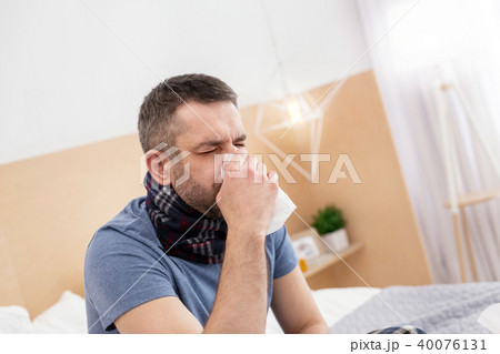Sick man blowing his nose 40076131