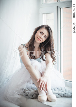 Beautiful ballerina girl is sitting on windowsill in studio Beautiful ballerina girl is sitting on windowsill in studio 40078211