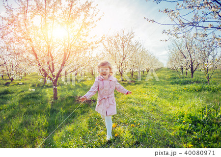 Little baby girl that runs between flowering trees at sunset. Ar Little baby girl that runs between flowering trees at sunset. Ar 40080971
