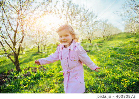 Little baby girl that runs between flowering trees at sunset. Ar Little baby girl that runs between flowering trees at sunset. Ar 40080972