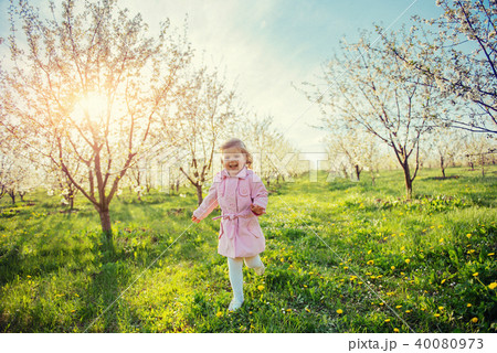 Little baby girl that runs between flowering trees at sunset. Ar Little baby girl that runs between flowering trees at sunset. Ar 40080973