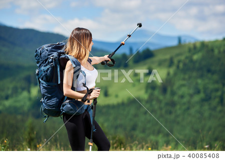 Sporty woman hiker with backpack and trekking sticks hiking in the mountains 40085408