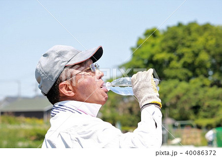 畑で水分補給するシニア 40086372