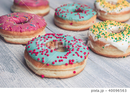 Donuts with colorful icing on a wooden background. 40096563