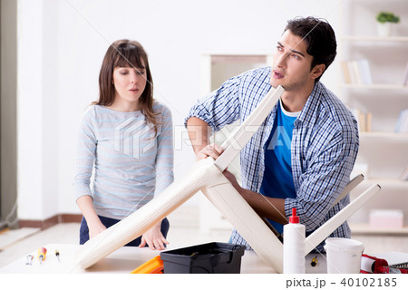 Wife helping husband to repair broken chair at home Wife helping husband to repair broken chair at home 40102185