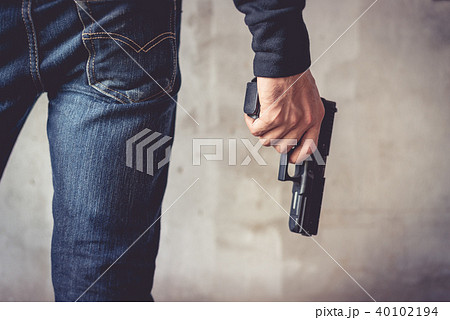 Close up of man holding gun. Man wearing jeans 40102194