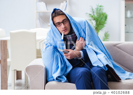 Employee businessman watching tv while being sick with flu Employee businessman watching tv while being sick with flu 40102688