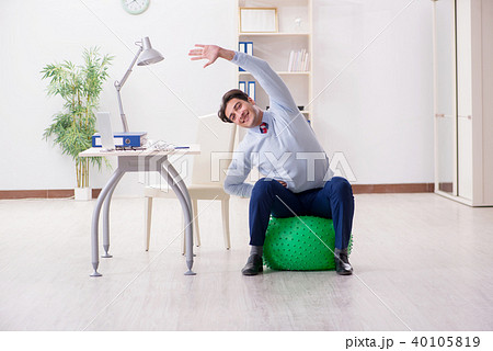 Employee exercising with swiss ball during lunch break Employee exercising with swiss ball during lunch break 40105819