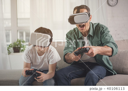 Excited man and boy entertaining with vr headsets Excited man and boy entertaining with vr headsets 40106113