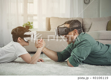 Excited father and son lying on floor and arm-wrestling 40106119