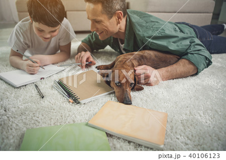 Joyful man helping child to do homework near pet 40106123