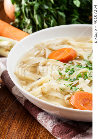 Tasty meat broth with noodles, carror and parsley Tasty meat broth with noodles, carror and parsley 40107204