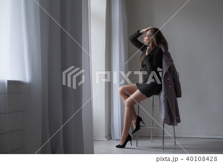 girl with gray coat sits on a Chair looking out of the window girl with gray coat sits on a Chair looking out of the window 40108428