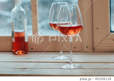 A bottle of rose wine and two glasses on a sill A bottle of rose wine and two glasses on a sill 40109118