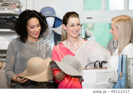 Girlfriends on shopping spree trying ladies hats 40112237
