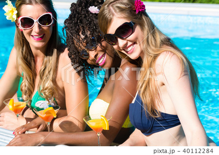 Friend drinking cocktails in swimming pool bar 40112284