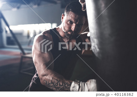 Male boxer training with punching bag in dark sports hall. 40116362