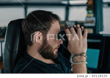 Deck navigation officer on the navigation bridge. He looks through binoculars 40118520