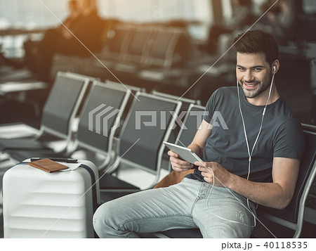 Cheerful male listening music with gadget in hall Cheerful male listening music with gadget in hall 40118535