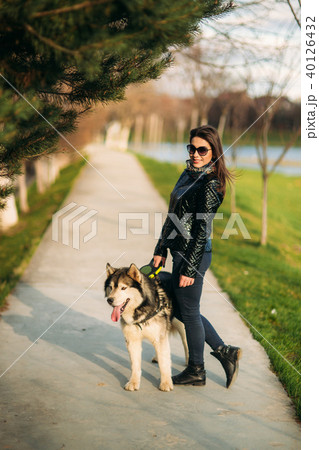 Beautiful brunette lady walking with a dog along the embankment. Beautiful husky dog 40126432