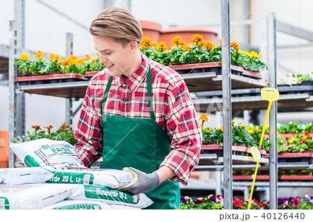 Young man carrying a bag of potting soil during work at the flower market 40126440