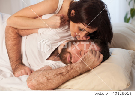 woman gently wakes up in the morning in bed man 40129013
